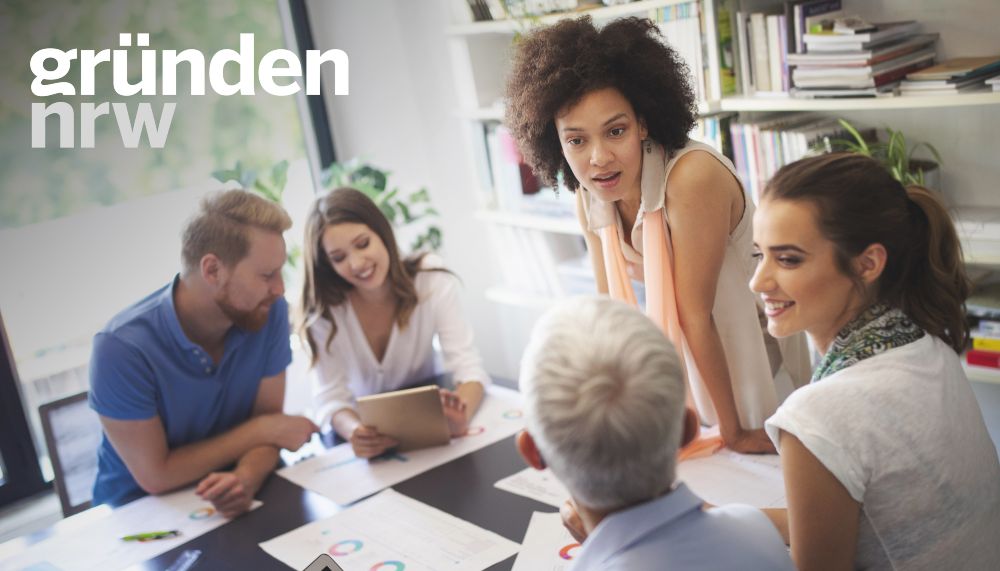 Eine Gruppe von Menschen sitzt zusammen an einem Tisch und diskutiert freundlich