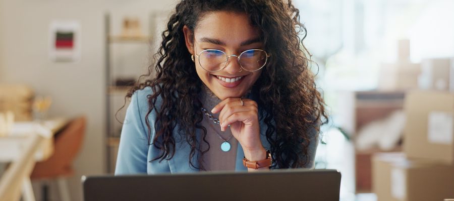 A woman is looking at a laptop with a smile.